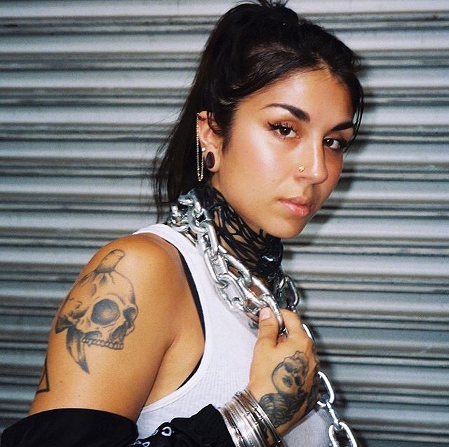 Yasmine Yousaf in a white sleeveless showing her tattoo.